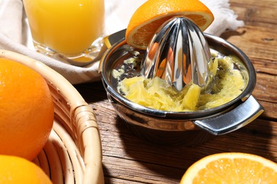 Photo of Freshly squeezed orange juice, fruits and juicer on wooden table, closeup