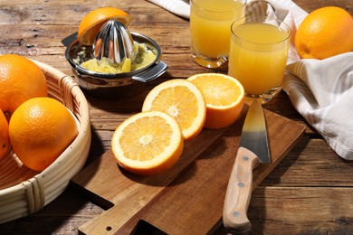 Photo of Freshly squeezed orange juice, fruits and juicer on wooden table, closeup