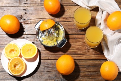 Photo of Freshly squeezed orange juice, fruits and juicer on wooden table, flat lay