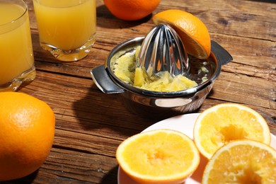 Photo of Freshly squeezed orange juice, fruits and juicer on wooden table, closeup