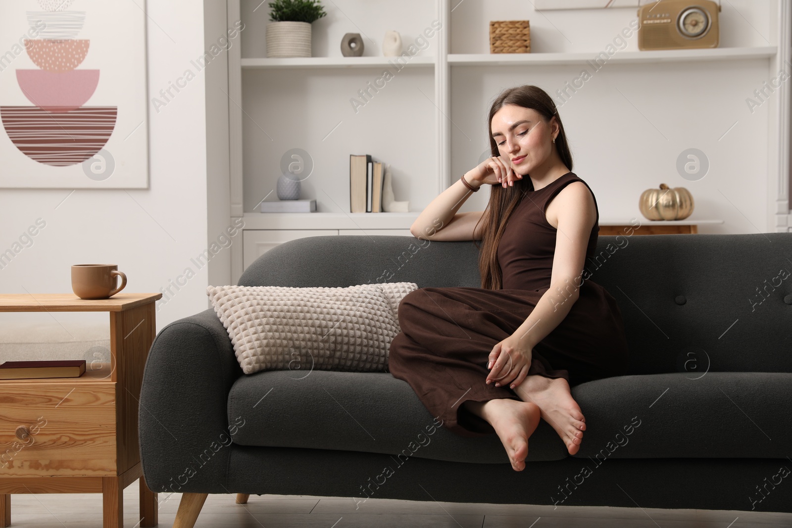Photo of Beautiful woman sitting on sofa at home