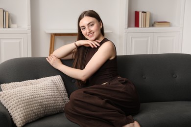 Photo of Beautiful woman sitting on sofa at home