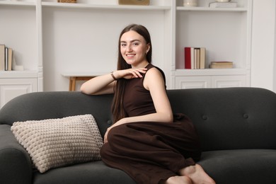 Photo of Beautiful woman sitting on sofa at home