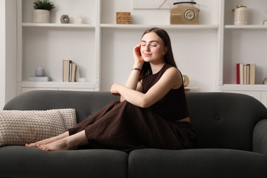 Photo of Beautiful woman sitting on sofa at home