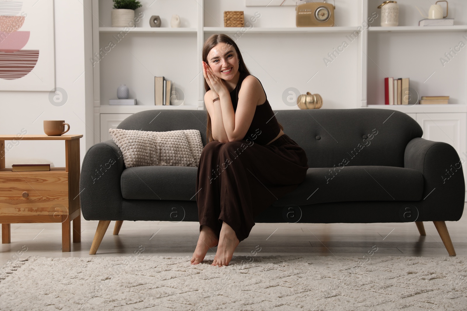 Photo of Beautiful woman sitting on sofa at home