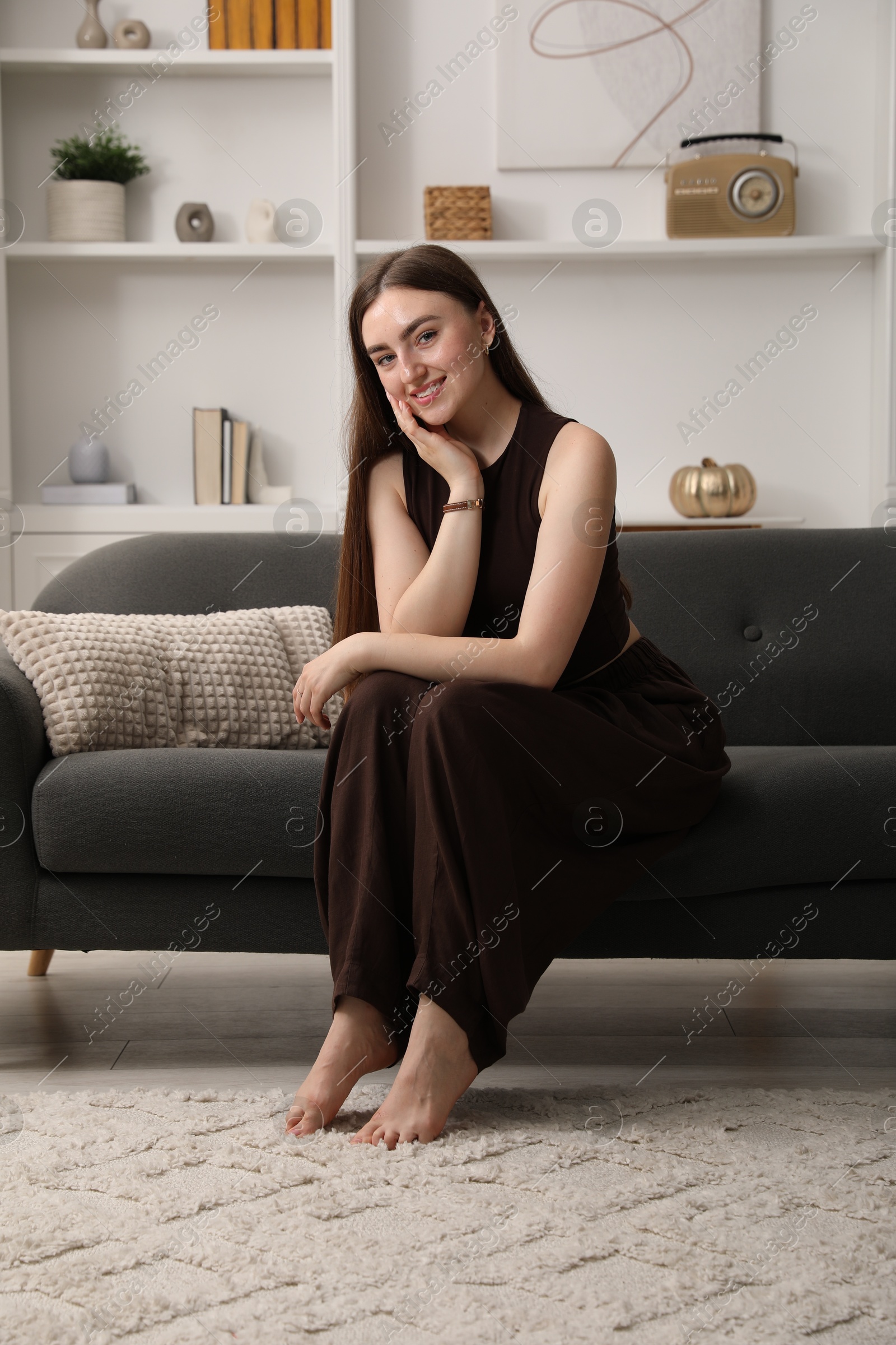 Photo of Beautiful woman sitting on sofa at home