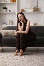 Photo of Beautiful woman sitting on sofa at home