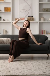 Photo of Beautiful woman sitting on sofa at home