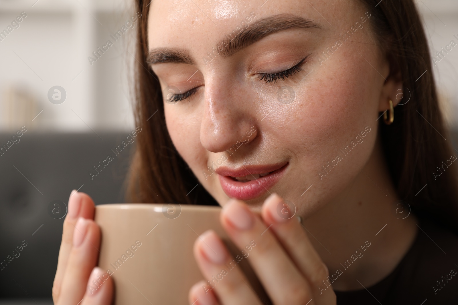 Photo of Beautiful woman with cup of drink at home, closeup