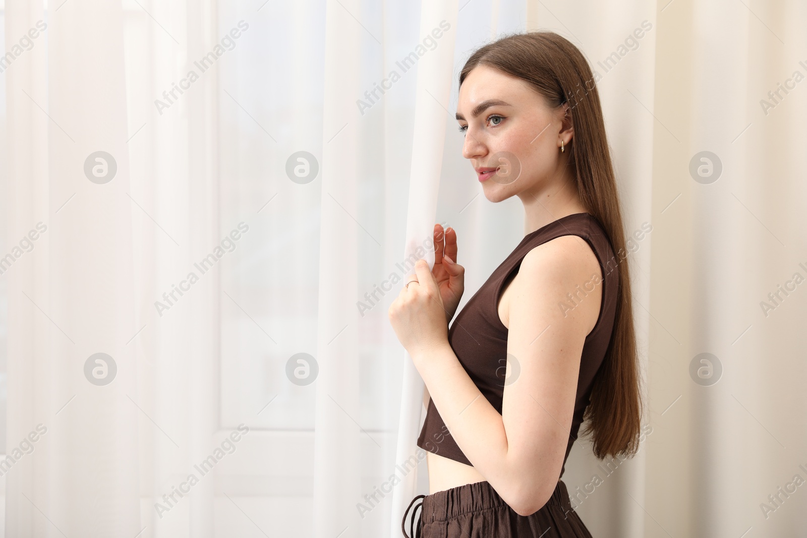 Beautiful woman near window at home, space for text Photo of Beautiful woman near window at home, space for text