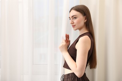 Photo of Beautiful woman near window at home, space for text