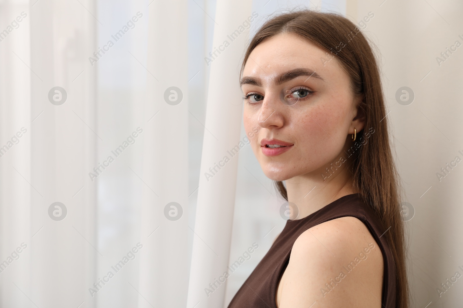 Beautiful woman near window at home, space for text Photo of Beautiful woman near window at home, space for text