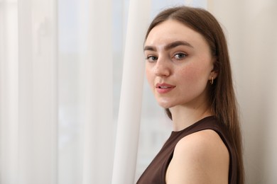 Photo of Beautiful woman near window at home, space for text