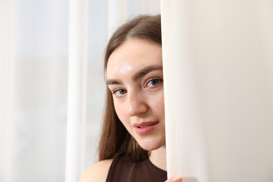 Photo of Beautiful woman near window with stylish curtains at home