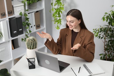 Photo of Woman having video chat via laptop at desk in office