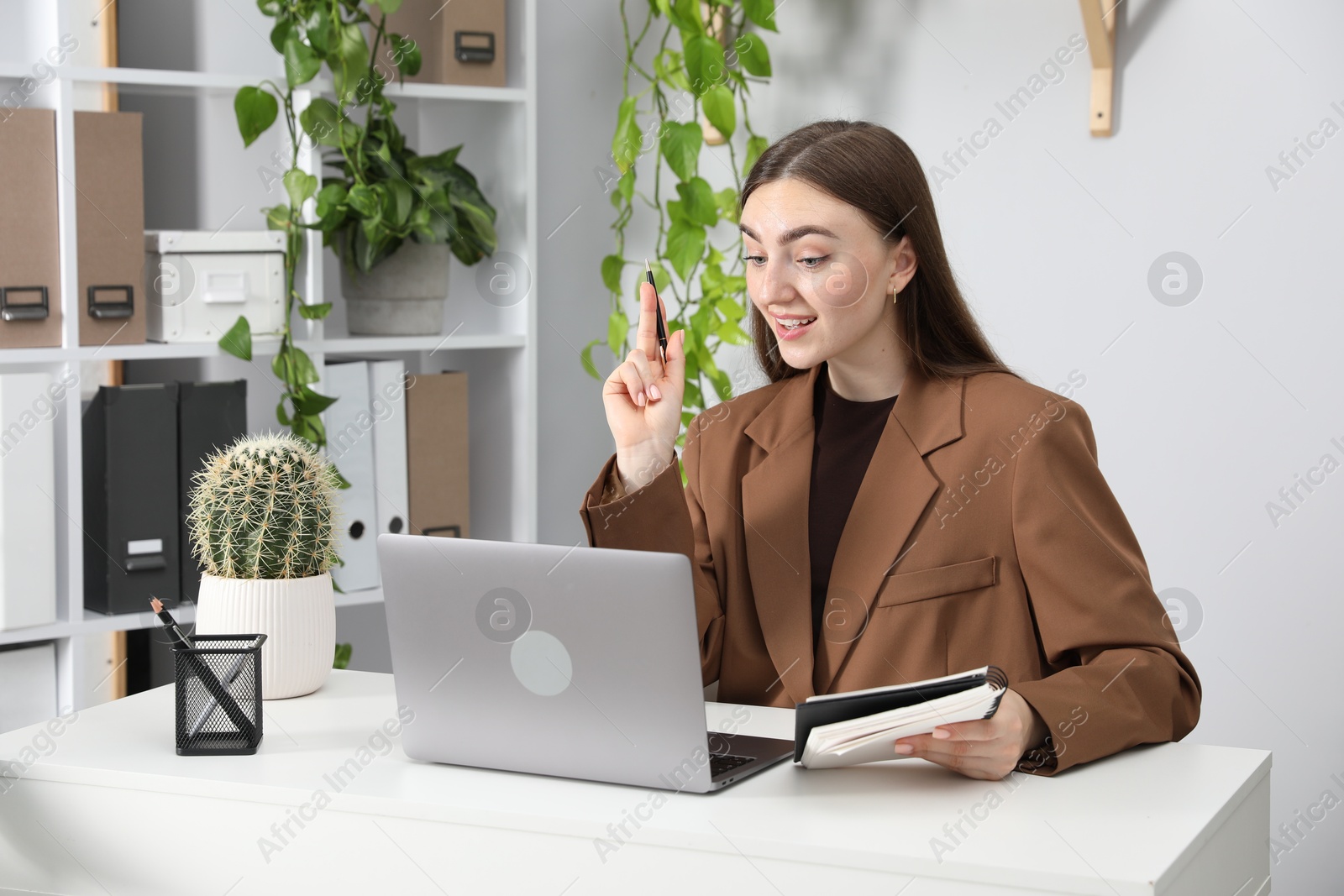 Woman having video chat via laptop at desk in office Photo of Woman having video chat via laptop at desk in office