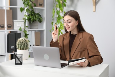 Photo of Woman having video chat via laptop at desk in office