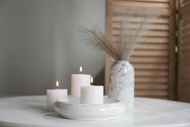 Photo of Burning candles on white table at home. Space for text