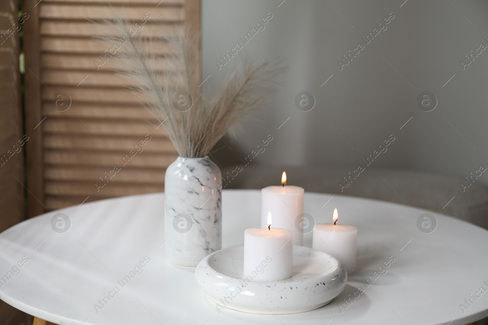 Photo of Burning candles on white table at home. Space for text
