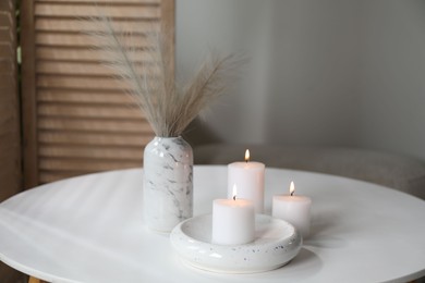 Photo of Burning candles on white table at home. Space for text