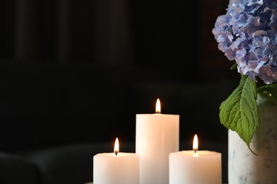 Photo of Burning candles and hydrangea flowers at home, closeup. Space for text