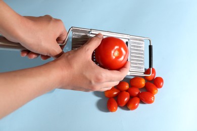 Photo of Woman with grater and tomatoes on light blue background, top view