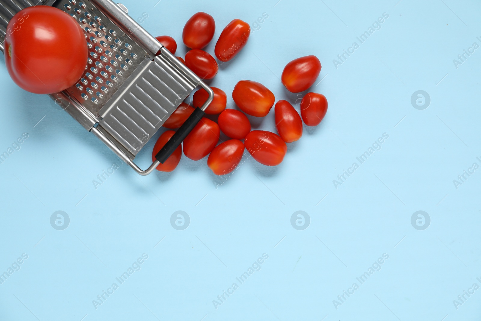 Fresh tomatoes and grater on light blue background, flat lay. Space for text Photo of Fresh tomatoes and grater on light blue background, flat lay. Space for text