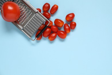 Photo of Fresh tomatoes and grater on light blue background, flat lay. Space for text