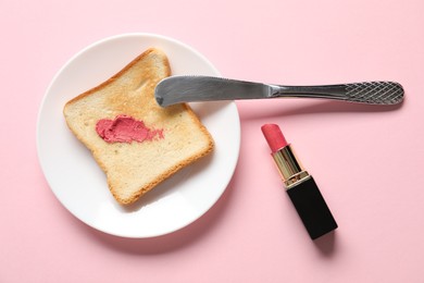 Photo of Toast with lipstick and butter knife on light pink background, flat lay