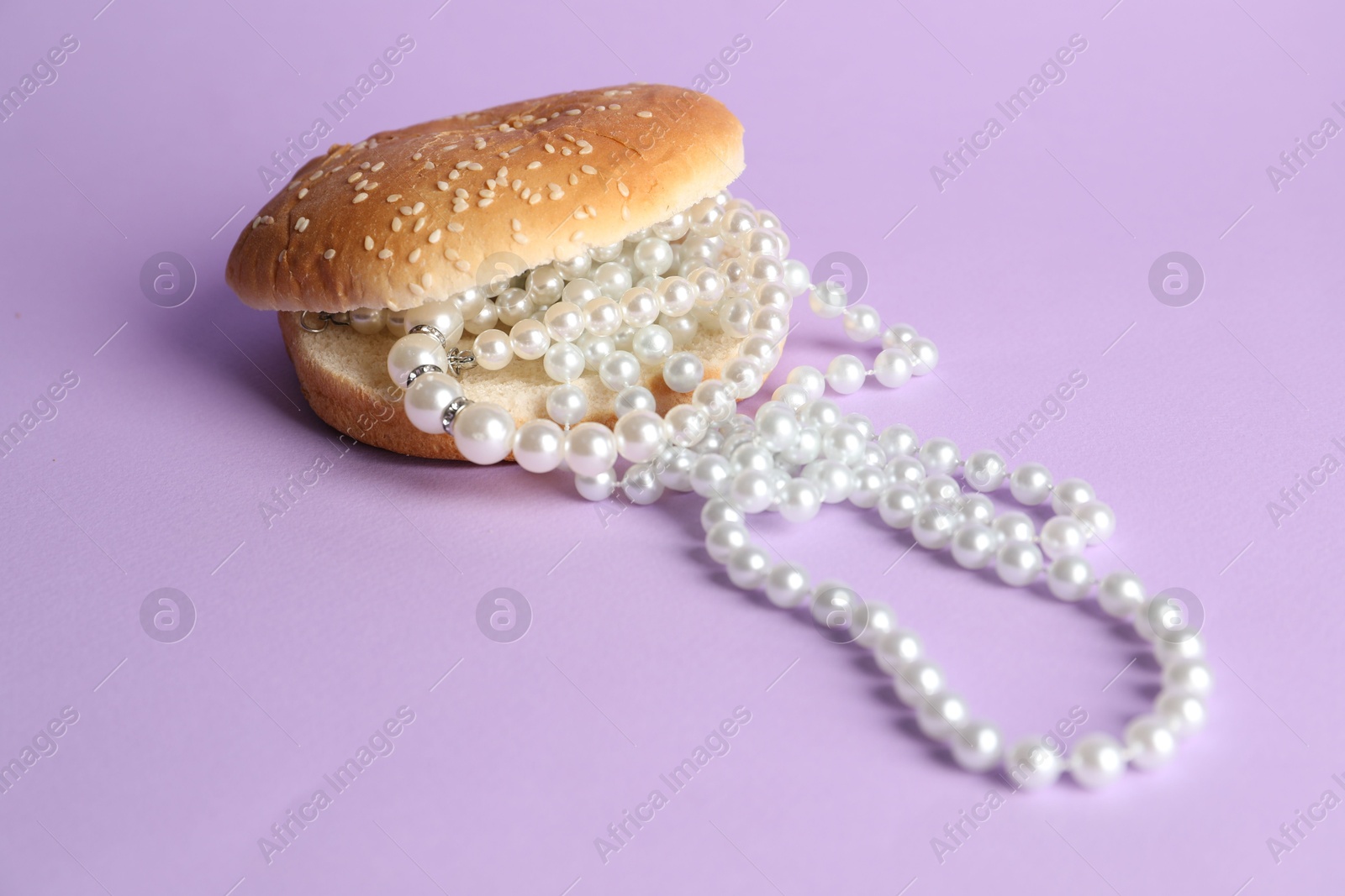 Photo of Burger with pearl necklace on lilac background, closeup