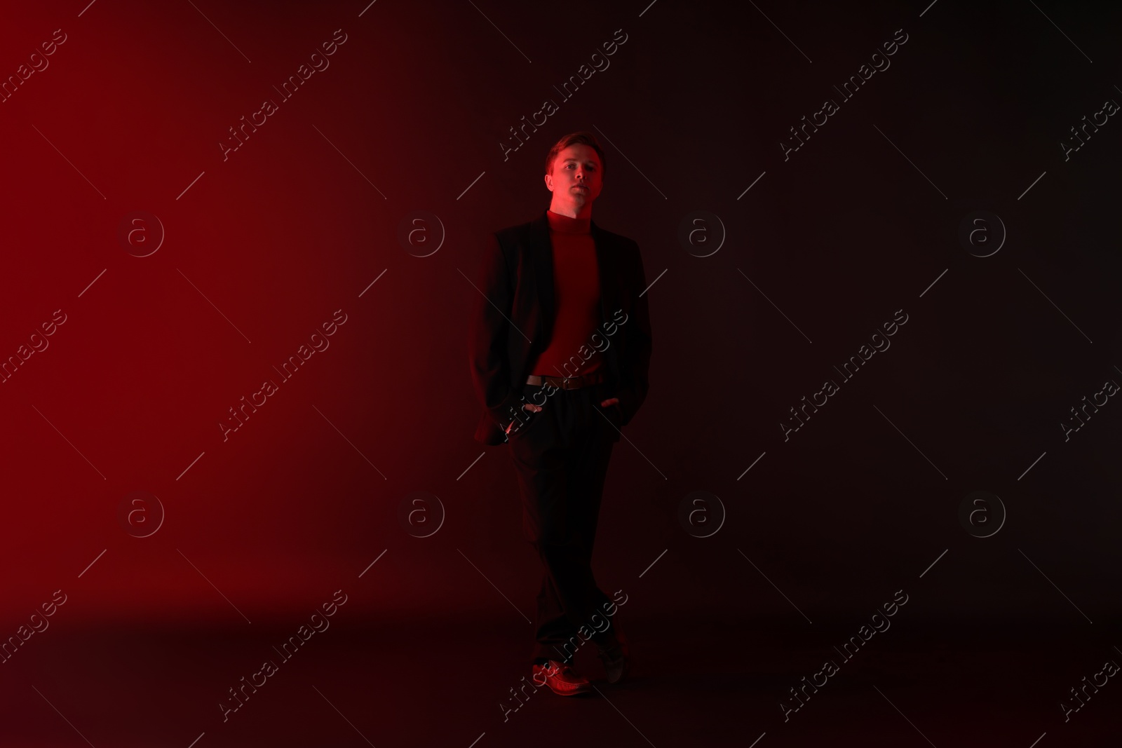 Handsome man wearing suit standing in neon lights against dark background Photo of Handsome man wearing suit standing in neon lights against dark background