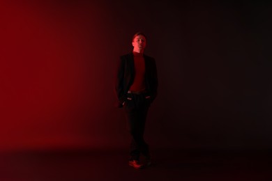 Photo of Handsome man wearing suit standing in neon lights against dark background