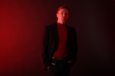 Photo of Portrait of handsome man wearing suit in neon lights against dark background