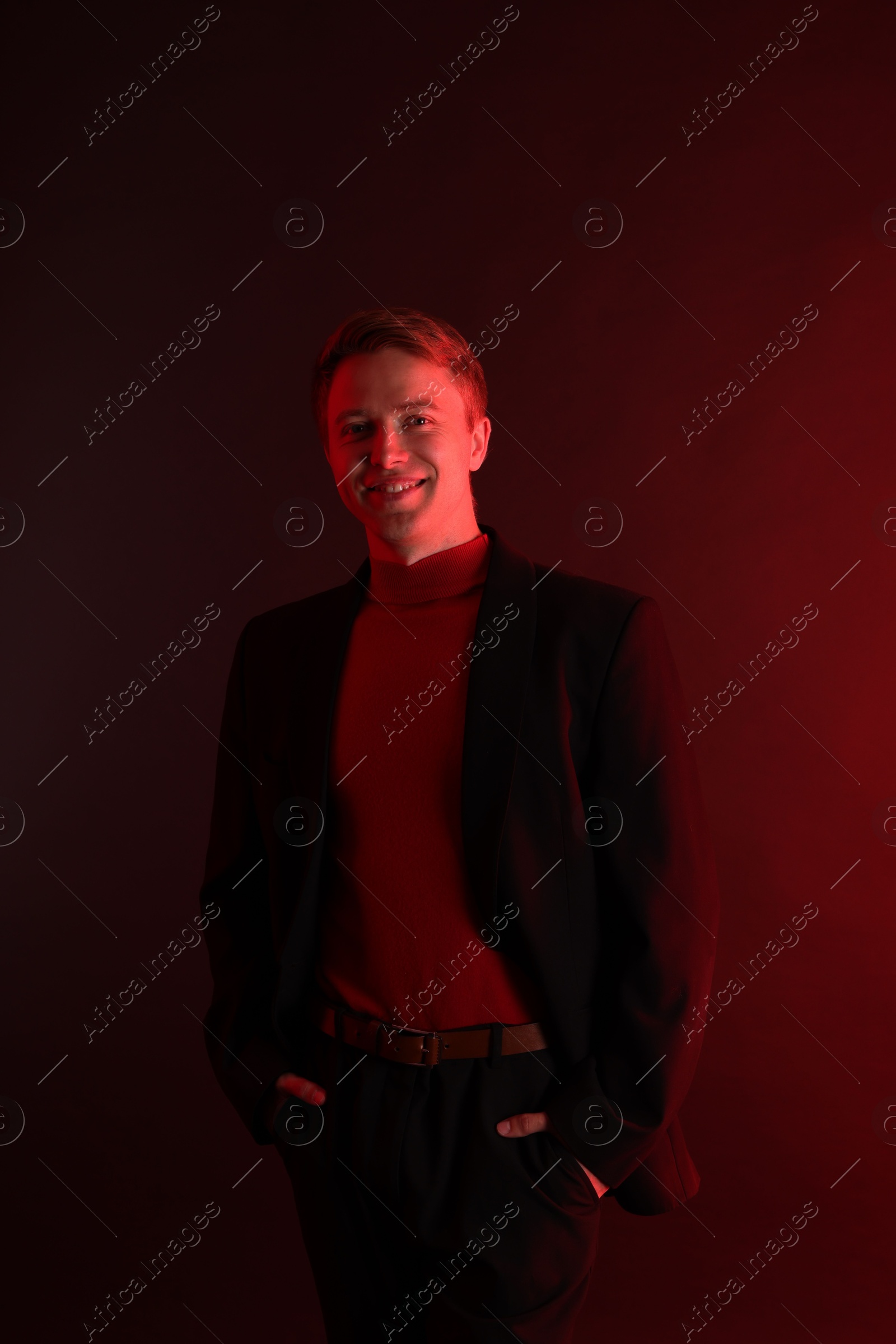 Portrait of smiling man wearing suit in neon lights against dark background Photo of Portrait of smiling man wearing suit in neon lights against dark background