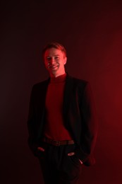 Photo of Portrait of smiling man wearing suit in neon lights against dark background