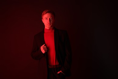 Photo of Portrait of handsome man wearing suit in neon lights against dark background