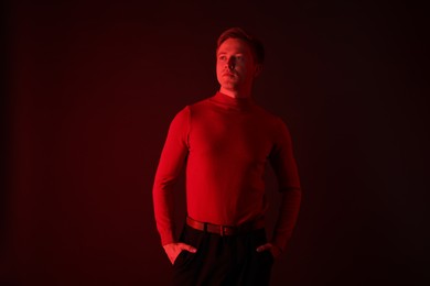 Photo of Handsome man in neon lights against dark background