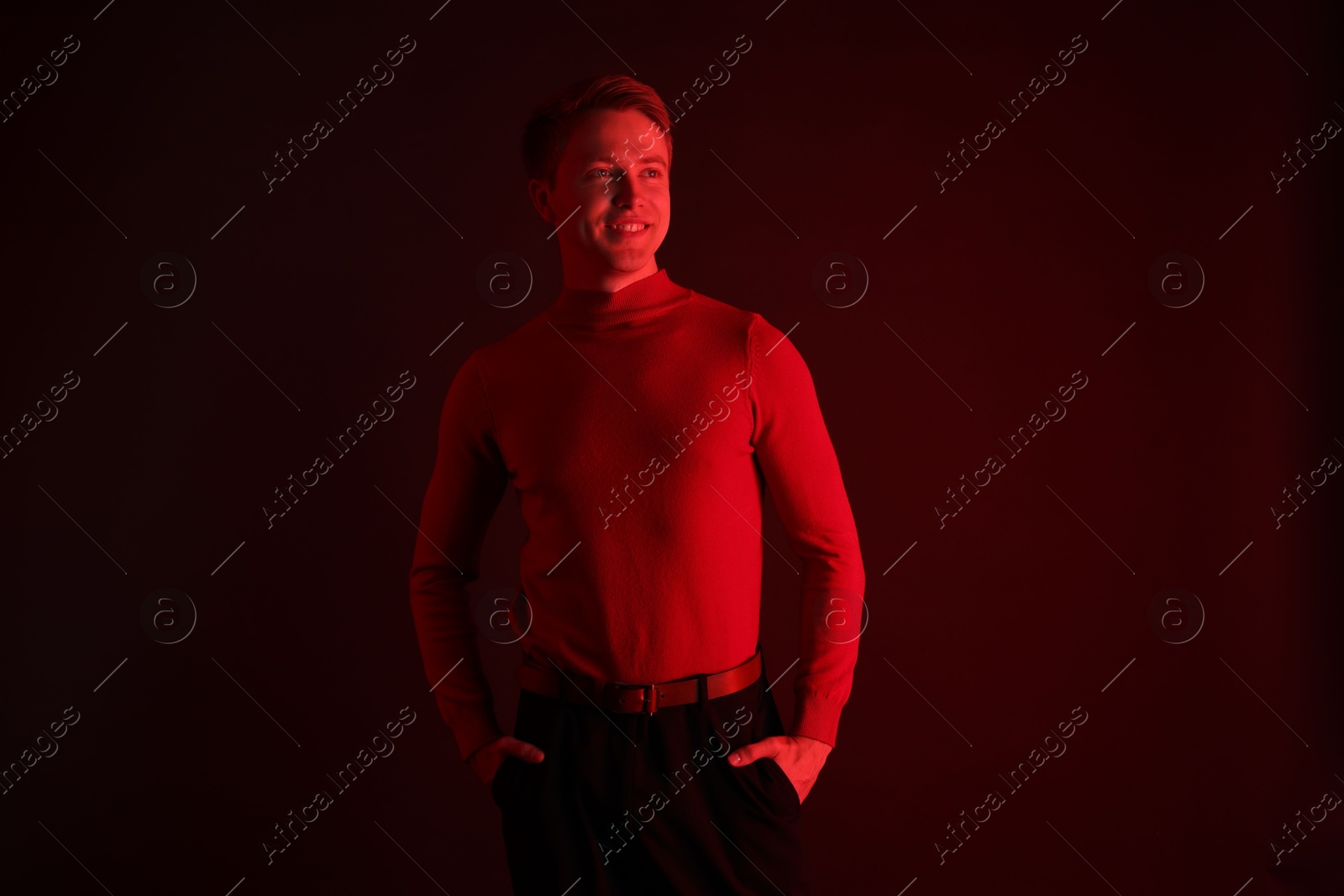 Smiling man in neon lights against dark background Photo of Smiling man in neon lights against dark background