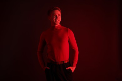 Photo of Smiling man in neon lights against dark background
