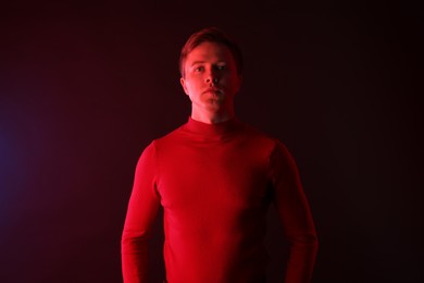 Photo of Portrait of handsome man in neon lights against dark background