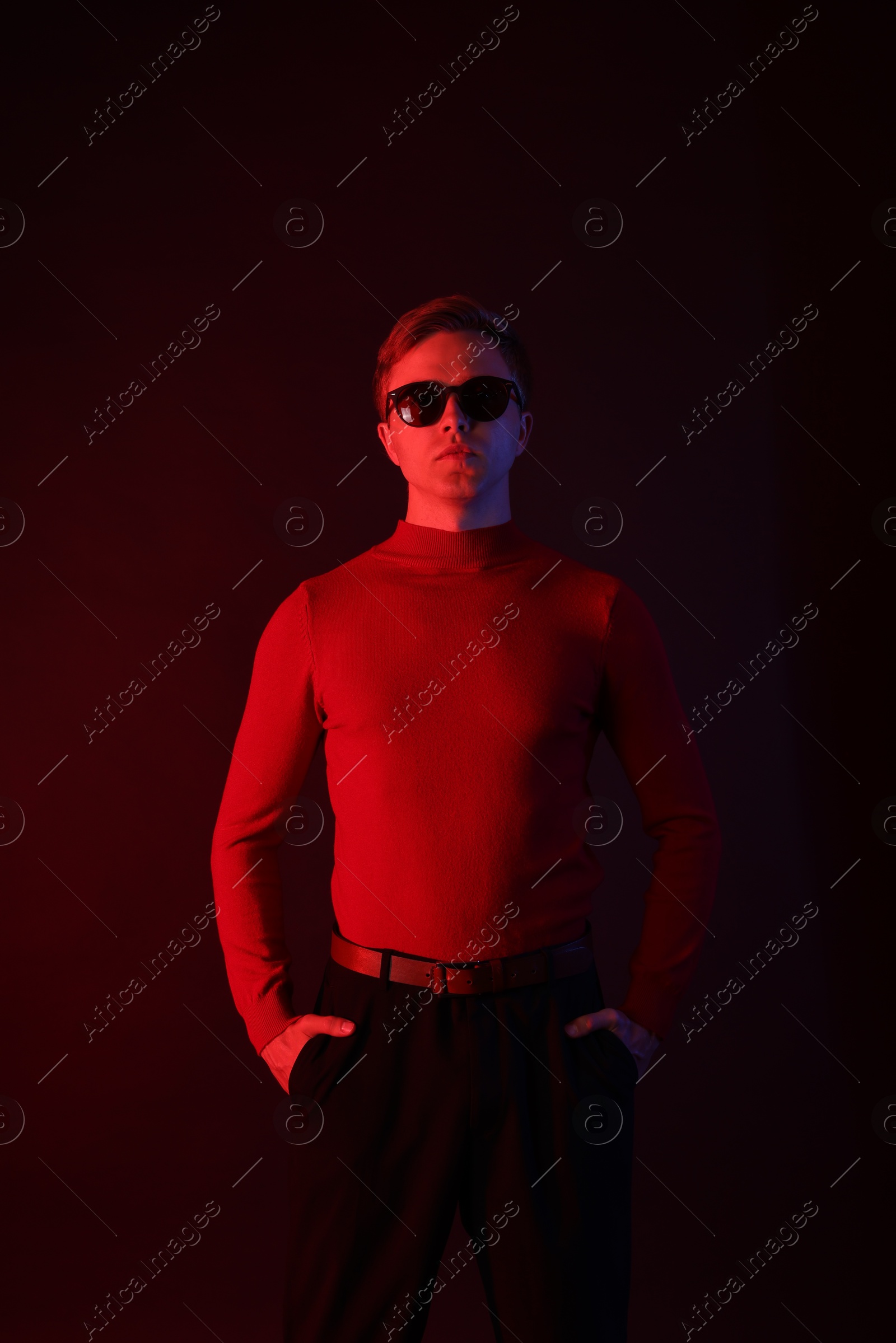 Handsome man wearing sunglasses in neon lights against dark background Photo of Handsome man wearing sunglasses in neon lights against dark background