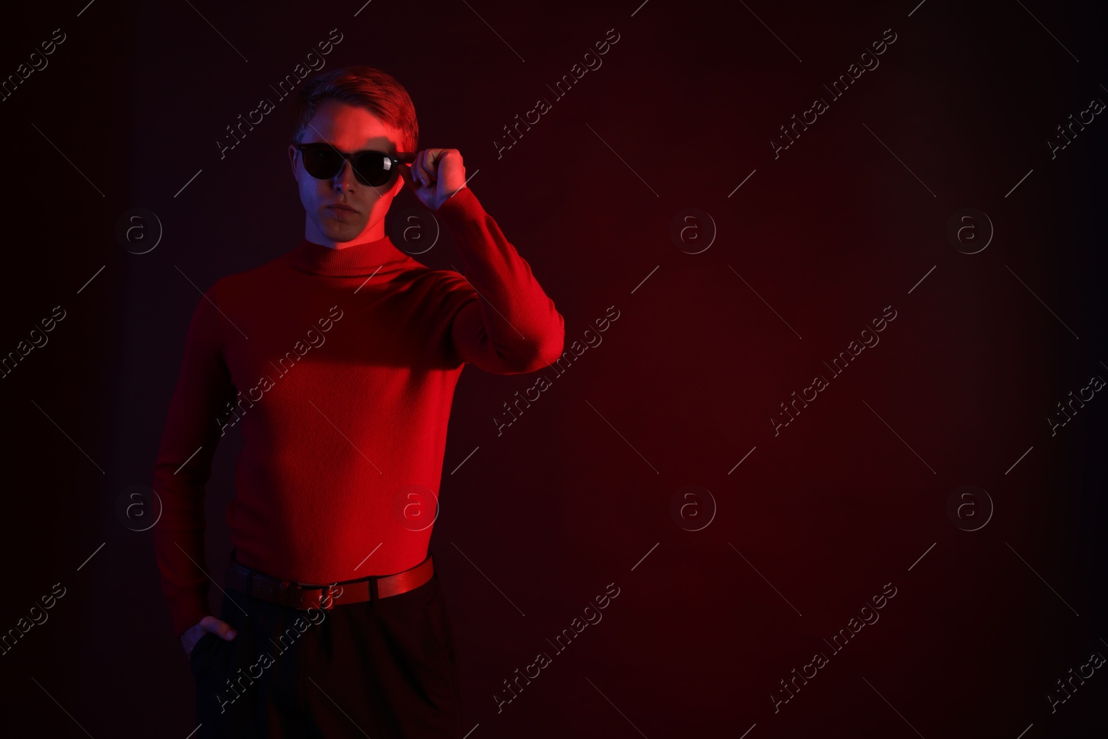 Handsome man wearing sunglasses in neon lights against dark background. Space for text Photo of Handsome man wearing sunglasses in neon lights against dark background. Space for text