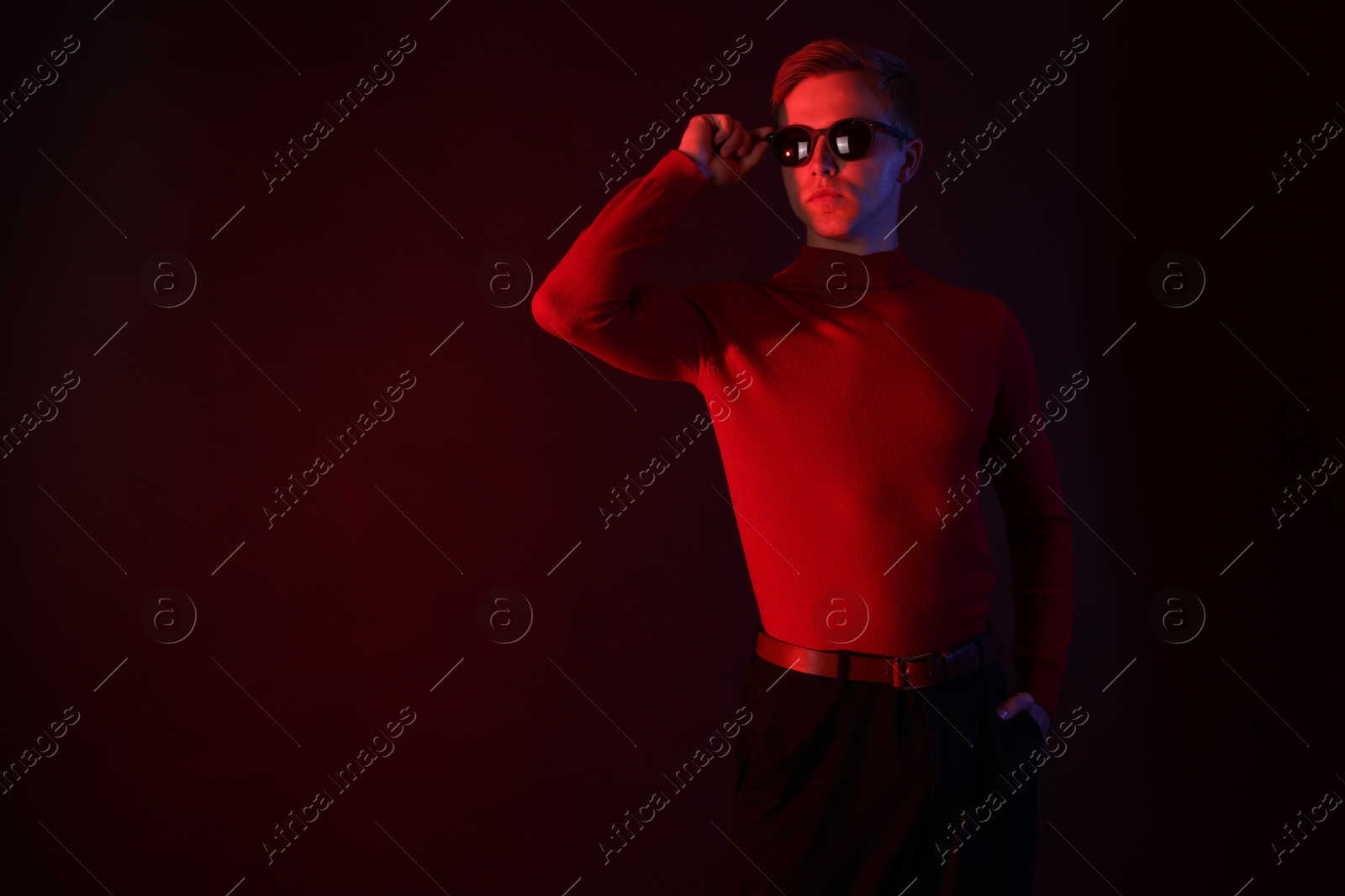 Handsome man wearing sunglasses in neon lights against dark background. Space for text Photo of Handsome man wearing sunglasses in neon lights against dark background. Space for text