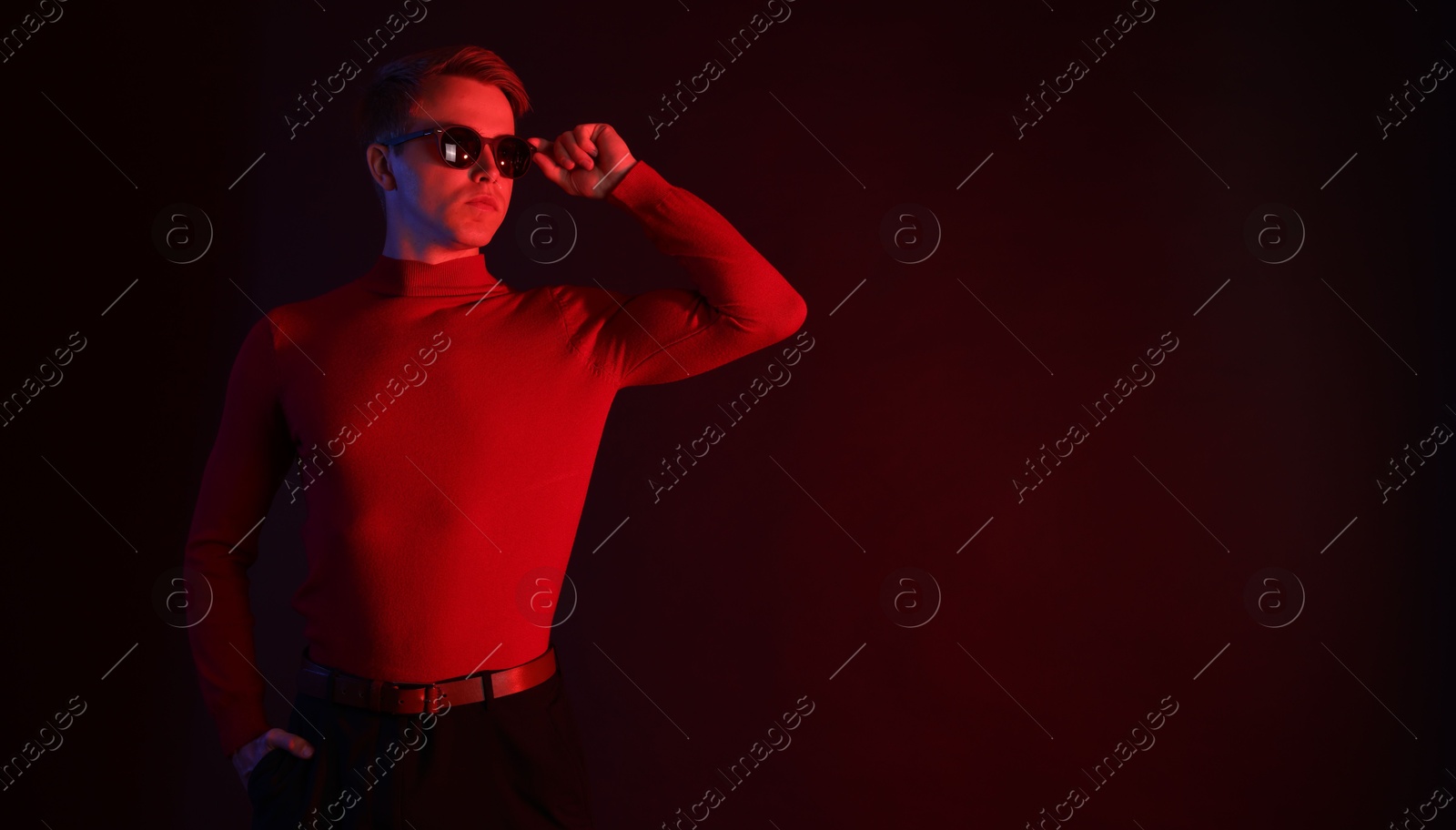 Handsome man wearing sunglasses in neon lights against dark background. Space for text Photo of Handsome man wearing sunglasses in neon lights against dark background. Space for text