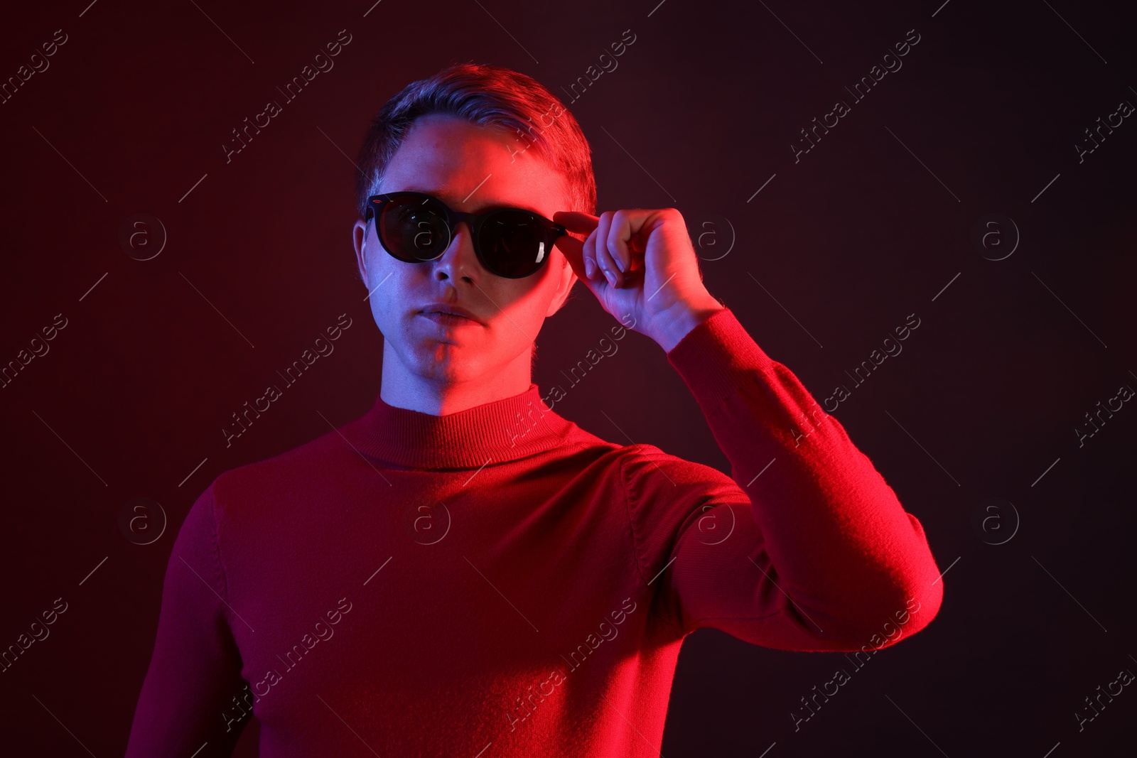 Handsome man wearing sunglasses in neon lights against dark background Photo of Handsome man wearing sunglasses in neon lights against dark background