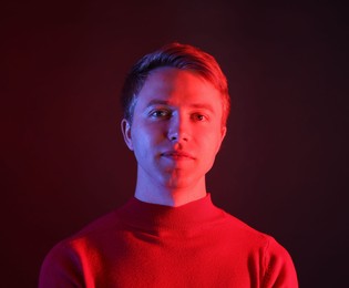 Photo of Portrait of handsome man in neon lights against dark background