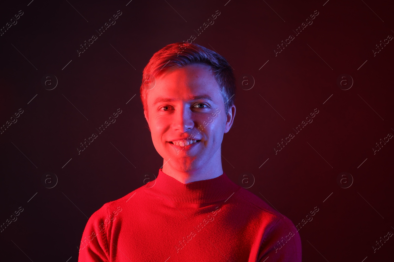 Portrait of smiling man in neon lights against dark background Photo of Portrait of smiling man in neon lights against dark background