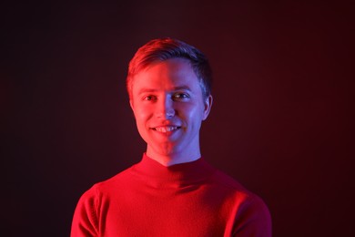 Photo of Portrait of smiling man in neon lights against dark background