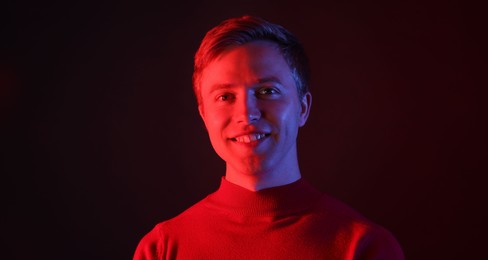 Photo of Portrait of smiling man in neon lights against black background
