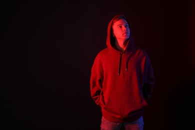 Photo of Handsome man in neon lights against black background. Space for text